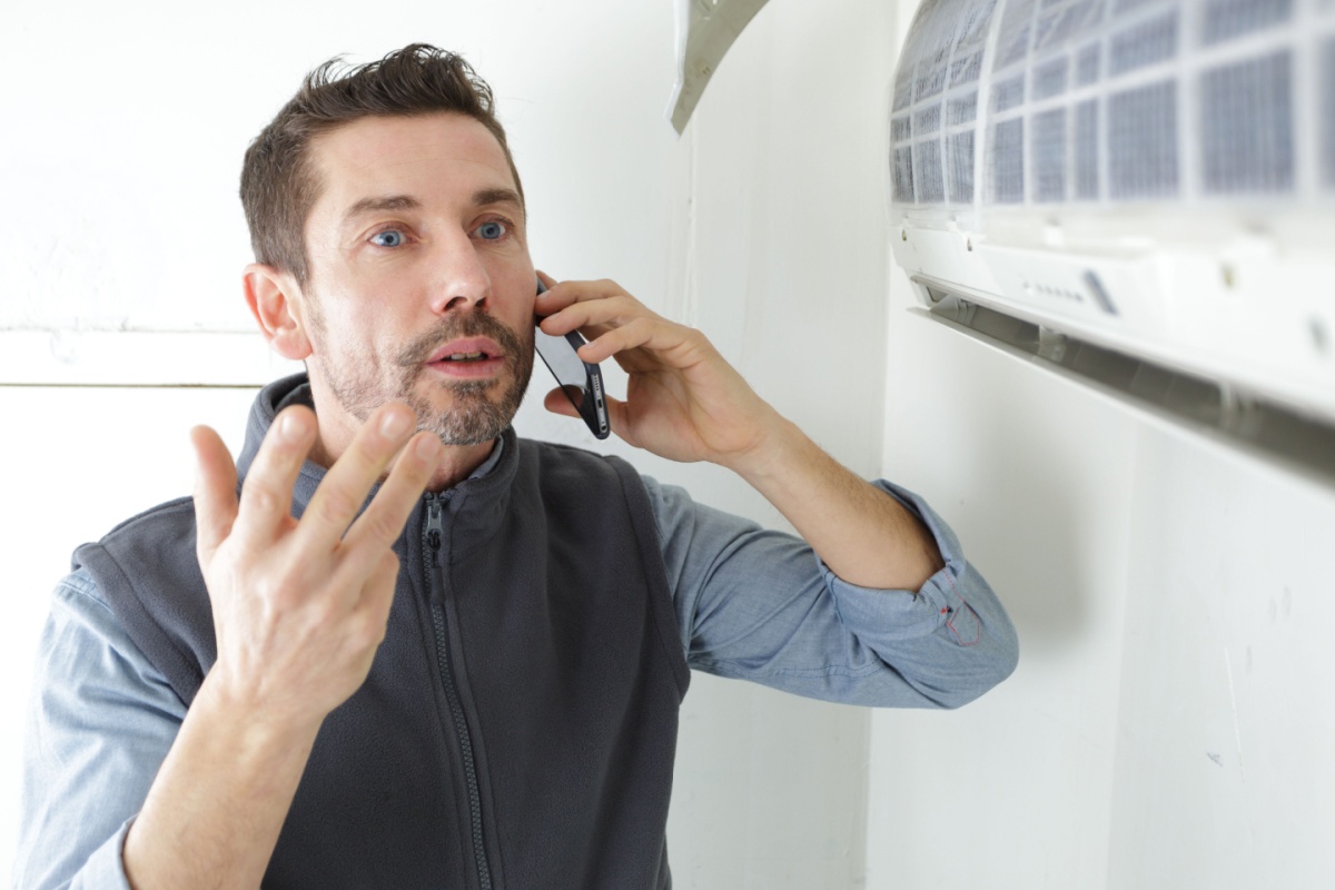 Man on the phone with an HVAC technician as he explains a problem with his mini split HVAC unit