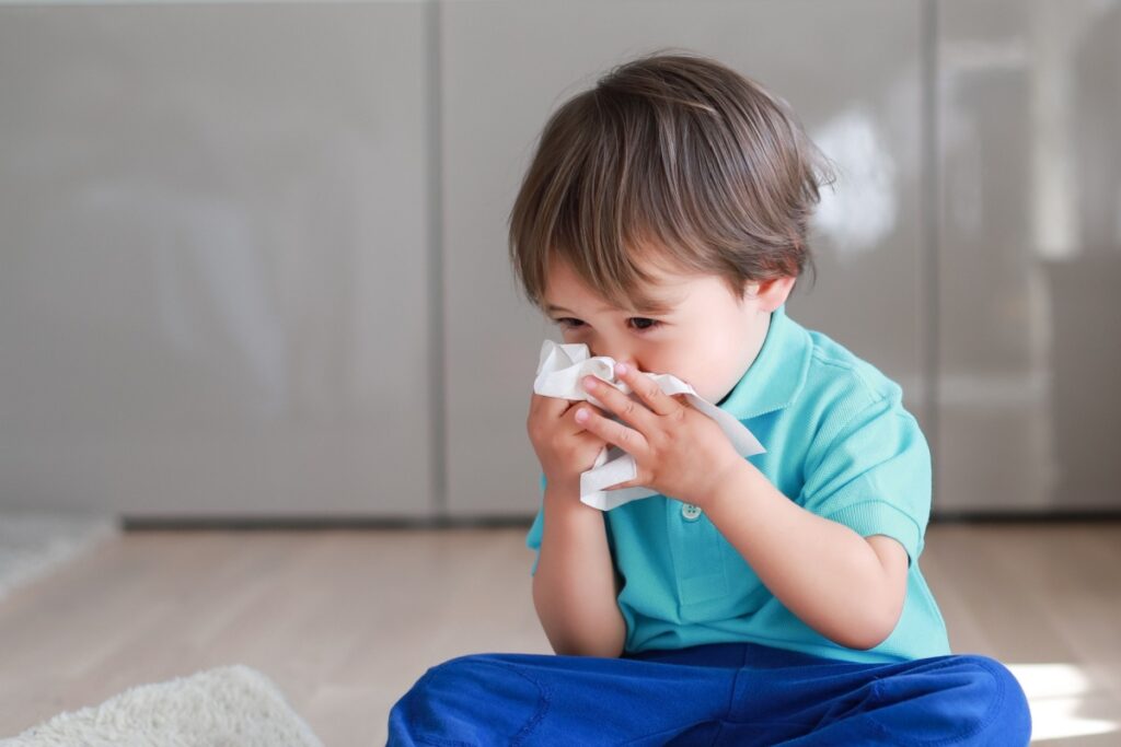 A young boy with allergies, blowing his nose