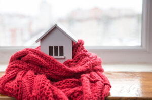 A miniature home wrapped in a scarf to show how cold it is