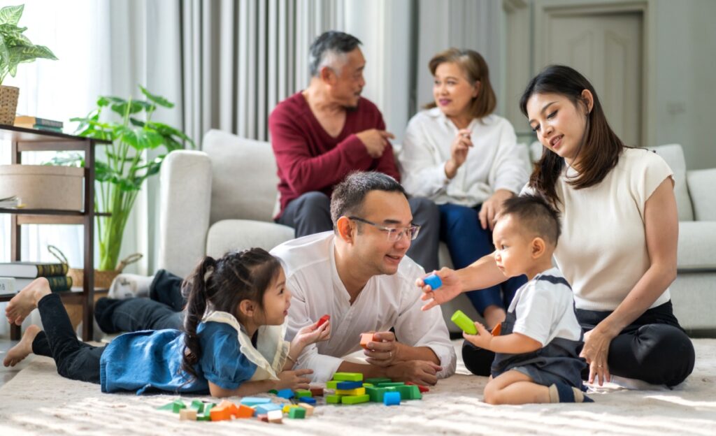 A family of three generations sitting on the floor playing with the young kids