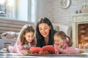 mother and two daughters lying on the floor, reading together