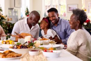 Three generations (grandparents, father, and daughter) sitting at the dinner table enjoying a holiday meal together