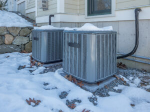 two outdoor HVAC units covered in snow