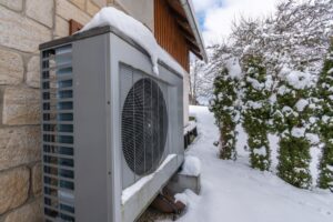 An outdoor heat pump unit covered in snow