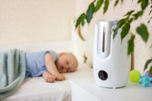 a baby sleeping during a nap with a humidifier in the foreground