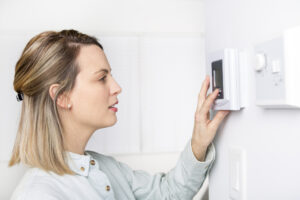 a woman adjusting the thermostat because it's not working